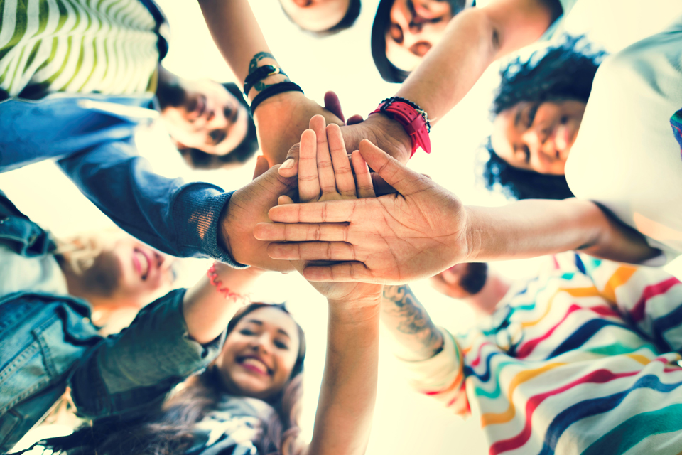 young people putting their hands together in a circle